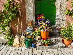 House with watering can, garden gnome, brooms and pots with plants.