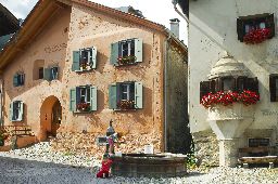 Two little girls playing at the fountain in the village in Engadine, Graubunden, Switzerland.
