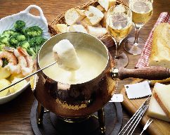 A fondue pot containing a melted substance and a cube of bread.