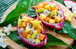Exotic fruit salad served in half a dragon fruit on palm leaves