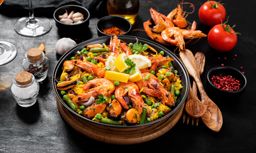 Traditional spanish seafood paella in the fry pan on a black wooden table.