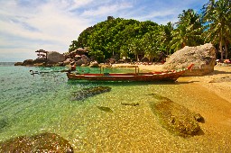Exotic beach with long-tailed boat anchored at the shore